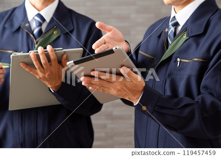 A middle-aged male businessman in work clothes working on a tablet A middle-aged male businessman in work clothes working on a tablet 119457459