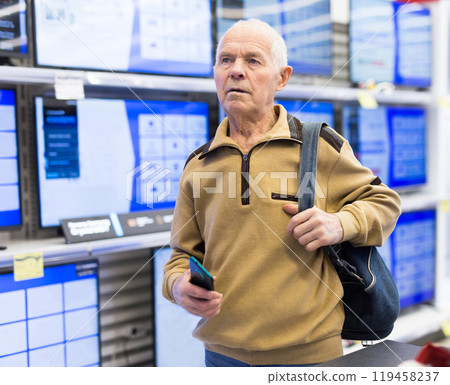 Elderly man choosing TV in showroom of electronics store 119458237
