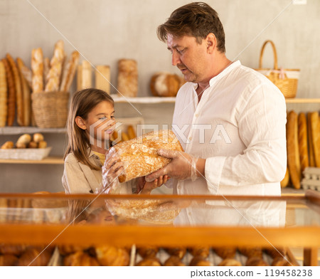 Dad and daughter customers holding loaf of bread and baguettes with hands in disposable gloves Dad and daughter customers holding loaf of bread and baguettes with hands in disposable gloves 119458238