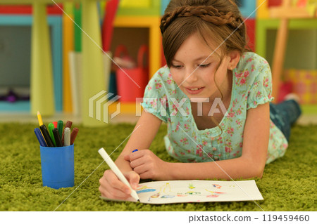 girl in the nursery draws lying on the carpet. 119459460