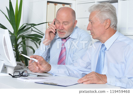 Two old business men sitting at desk and working 119459468
