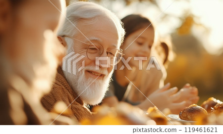 Enjoyable family meal outdoors, featuring elderly man and young girl sharing moments of happiness. 119461621