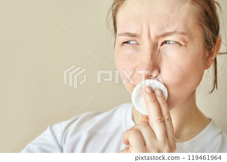 Woman contemplating skincare routine with cotton pad in natural light indoor 119461964