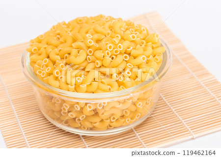 Uncooked Chifferi Rigati Pasta in Glass Jar on Bamboo Mat on White Background 119462164