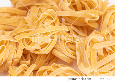 Scattered Classic Italian Raw Egg Fettuccine on White Table 119462448