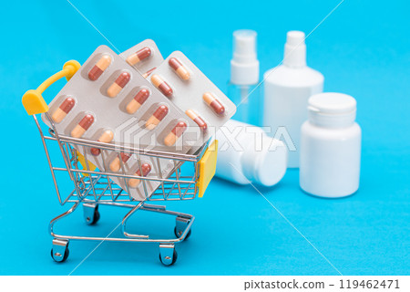 Pills and Capsules in Shopping Cart on Blue Background Pills and Capsules in Shopping Cart on Blue Background 119462471