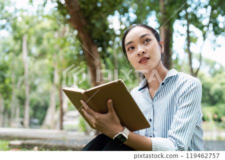 Young Digital Nomad Enjoying Outdoor Work Environment with Laptop and Notebook in a Park Setting Young Digital Nomad Enjoying Outdoor Work Environment with Laptop and Notebook in a Park Setting 119462757
