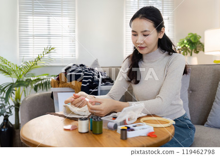 Young Woman Engaged in Hand Embroidery at Home with Sewing Supplies on a Wooden Table 119462798