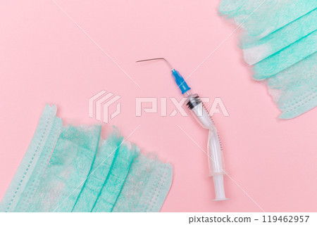 Broken Medical Syringe and Torn Medical Face Mask on the Pink Background 119462957