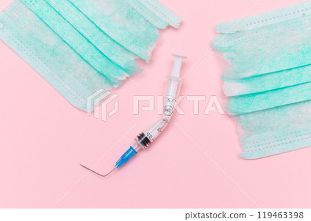 Broken Medical Syringe and Torn Medical Face Mask on the Pink Background 119463398