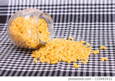 Scattered Uncooked Chifferi Rigati Pasta on Black Checkered Towel 119463412