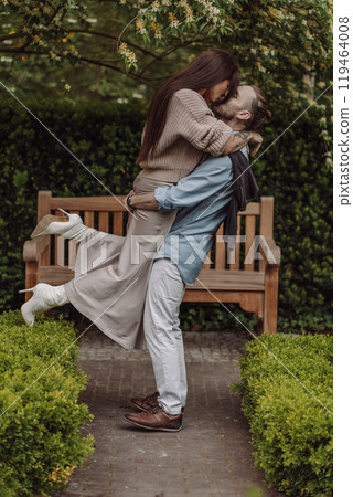 Happy loving couple enjoying their time together in park. Loving couple spending time together. Girl with tattoos. Tattooed woman. Beautiful fashionable couple of lovers on the street. 119464008