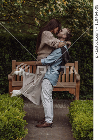 Happy loving couple enjoying their time together in park. Loving couple spending time together. Girl with tattoos. Tattooed woman. Beautiful fashionable couple of lovers on the street. 119464009