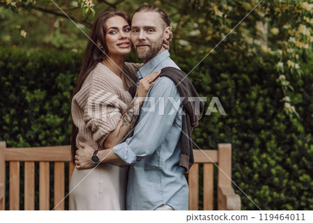 Happy loving couple enjoying their time together in park. Loving couple spending time together. Girl with tattoos. Tattooed woman. Beautiful fashionable couple of lovers on the street. 119464011