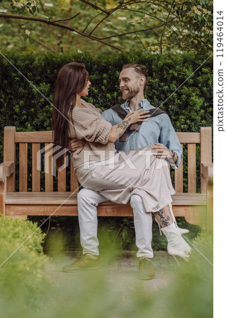 Happy loving couple enjoying their time together in park. Loving couple spending time together. Girl with tattoos. Tattooed woman. Beautiful fashionable couple of lovers on the street. 119464014