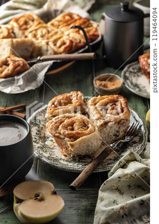 Autumn apple cinnamon rolls with frosting on green wooden background. Seasonal autumn homemade pastry cinnabons for breakfast 119464094