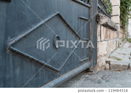 Elegant Blue Gate with Intricate Design in Quaint Stone Pathway Elegant Blue Gate with Intricate Design in Quaint Stone Pathway 119464316