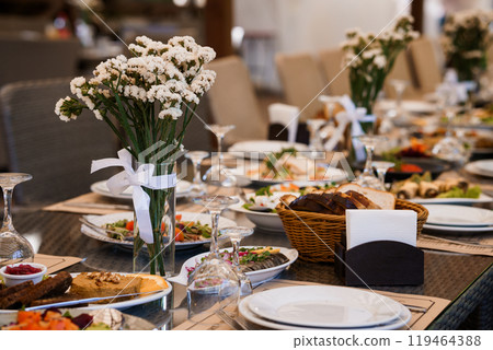 Elegant table setting adorned with fresh flowers and a variety of gourmet dishes for a festive occasion 119464388