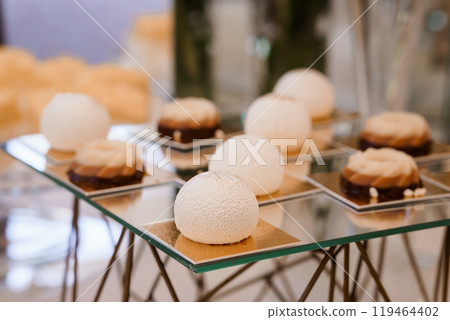 Elegant Display of Exquisite Pastry Creations on a Modern Glass Stand Elegant Display of Exquisite Pastry Creations on a Modern Glass Stand 119464402