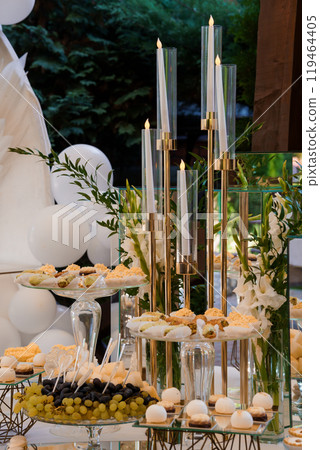 Elegant Wedding Dessert Table with Candlelit Ambiance and Floral Decor in an Outdoor Setting 119464405