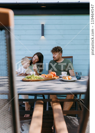 Family enjoying peaceful outdoor breakfast with fruits and coffee, bonding and creating memories Family enjoying peaceful outdoor breakfast with fruits and coffee, bonding and creating memories 119464547