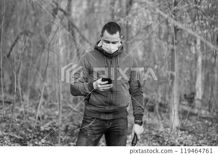 Man in Mask Texting in a Forest Setting Man in Mask Texting in a Forest Setting 119464761