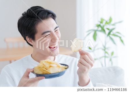 Smiling man eating potato chips 119466186