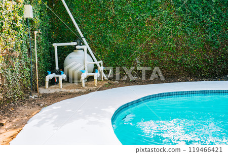 Pool pump with sand filter installed near of swimming pool. Home swimming pool filter and treatment plant installed. Pool purification and maintenance system Pool pump with sand filter installed near of swimming pool. Home swimming pool filter and treatment plant installed. Pool purification and maintenance system 119466421