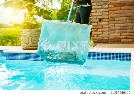 Person with skimmer cleaning a swimming pool. Hands holding a skimmer cleaning a pool. Man cleaning the pool with the Skimmer 119466665