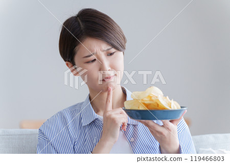 正在為是否吃薯片而煩惱的女性（薯片、節食、發胖、不健康） 119466803