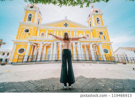Tourist woman spreading arms in front of a cathedral in a tourist square. Happy tourist in a tourist square. Granada, Nicaragua 119466913