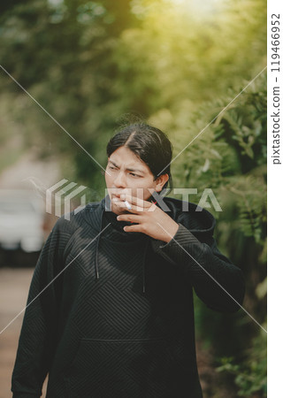 Young man smoking cigarette on the street. Portrait of handsome guy smoking outdoors 119466952