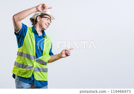 Smiling latin engineer pointing to the side with both fingers isolated. Happy male builder pointing an advertisement isolated 119466973