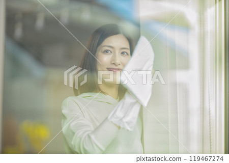 A middle-aged woman wiping windows in the living room A middle-aged woman wiping windows in the living room 119467274