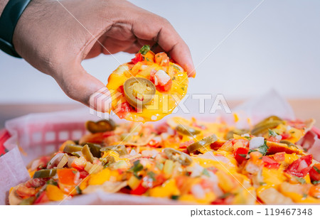 Close up of hand of taking nachos on isolated background. Hand taking and showing a nacho isolated Close up of hand of taking nachos on isolated background. Hand taking and showing a nacho isolated 119467348