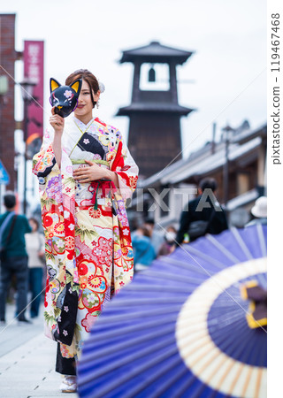 一位穿著長袖和服的年輕女子在時間鐘前擺姿勢 119467468