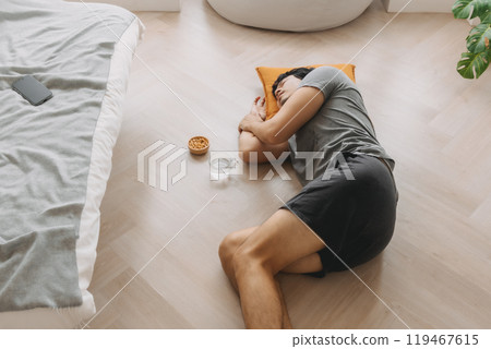 Wide angle of man napping on the floor in the living room. Wide angle of man napping on the floor in the living room. 119467615