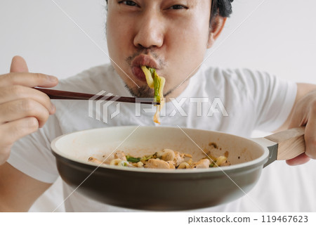 Close up of funny man eating his homemade lunch straight on the pan. 119467623