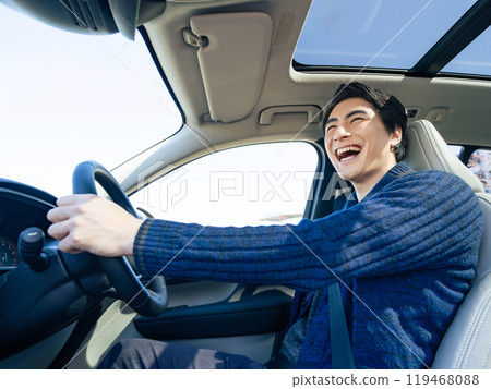 A scene in a car of a male driver driving a car with a smile A scene in a car of a male driver driving a car with a smile 119468088