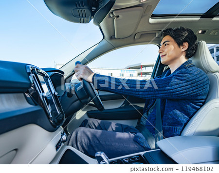Photo of a smiling male driver driving a car 119468102
