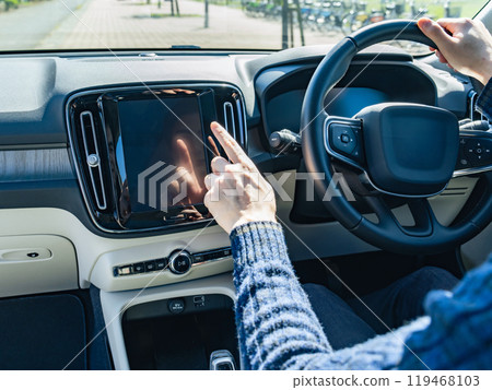 A driver touching the dashboard screen of a car A driver touching the dashboard screen of a car 119468103