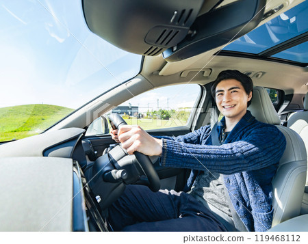 Photo of a smiling male driver driving a car Photo of a smiling male driver driving a car 119468112