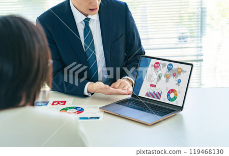 A group of business people discussing business in an office while looking at a laptop screen A group of business people discussing business in an office while looking at a laptop screen 119468130