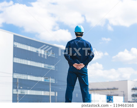 Back view of a male worker looking at a factory-like building 119468168