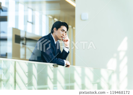 A male business person thinking deeply in the lobby of an office building A male business person thinking deeply in the lobby of an office building 119468172