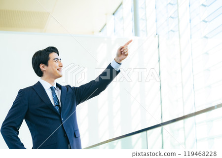 辦公大樓大廳裡,男性商務人士指著遠方 辦公大樓大廳裡,男性商務人士指著遠方 119468228