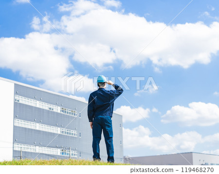 Back view of a male worker looking at a factory-like building 119468270