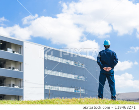 Back view of a male worker looking at a factory-like building 119468271