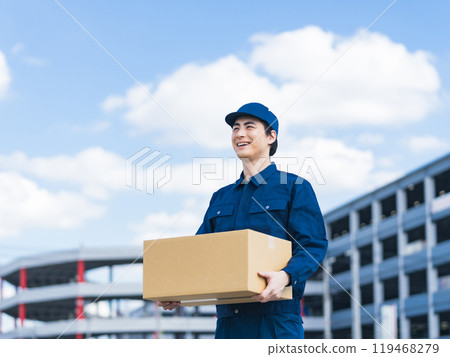 A delivery staff member carrying luggage in front of a building that looks like a logistics center A delivery staff member carrying luggage in front of a building that looks like a logistics center 119468279