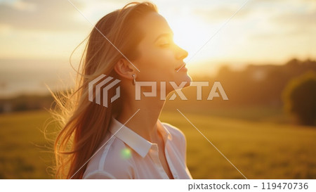 Young woman standing outdoors feeling the sun on her face 119470736